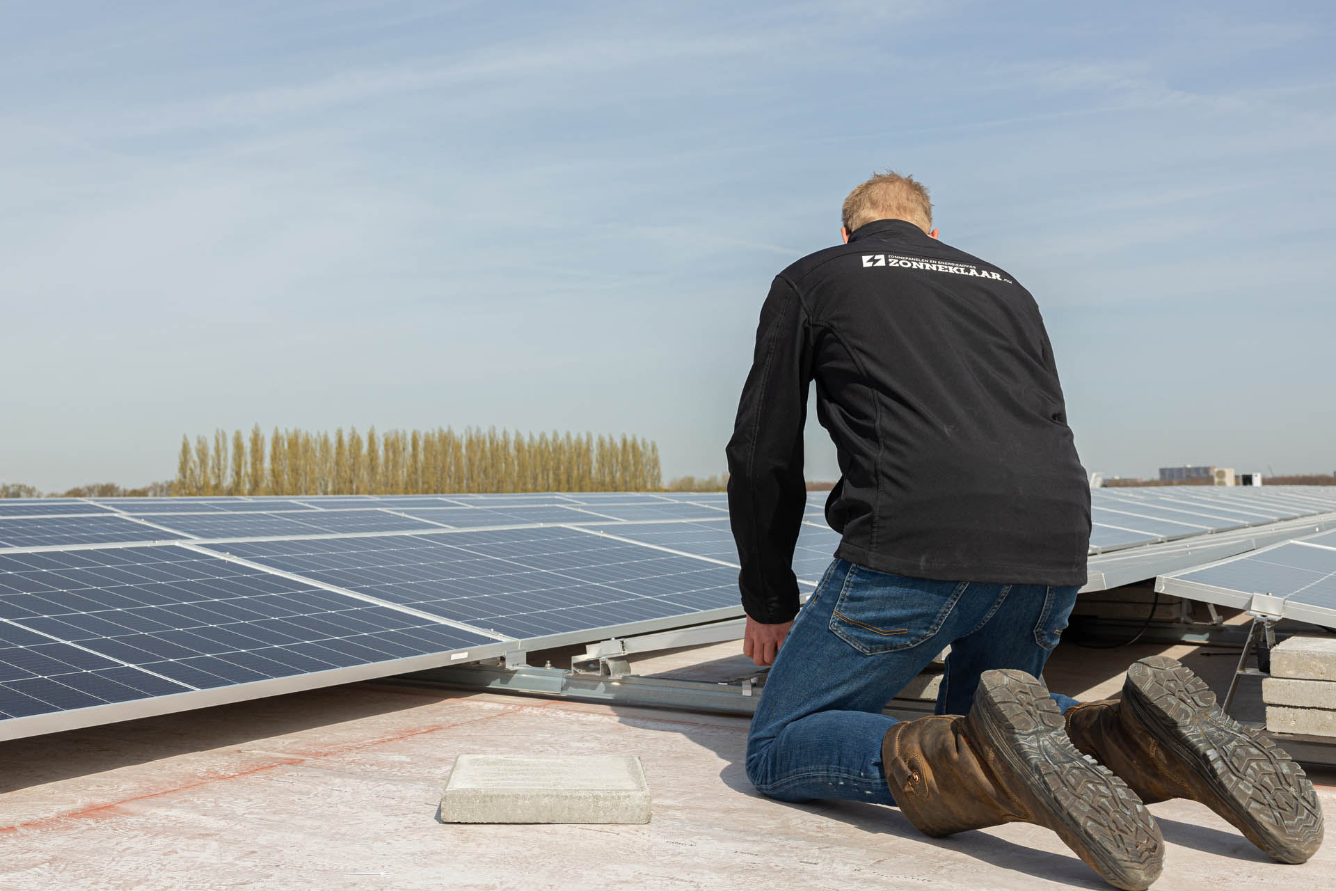 Een medewerker van Zonneklaar die bezig is met zakelijke zonnepanelen installeren