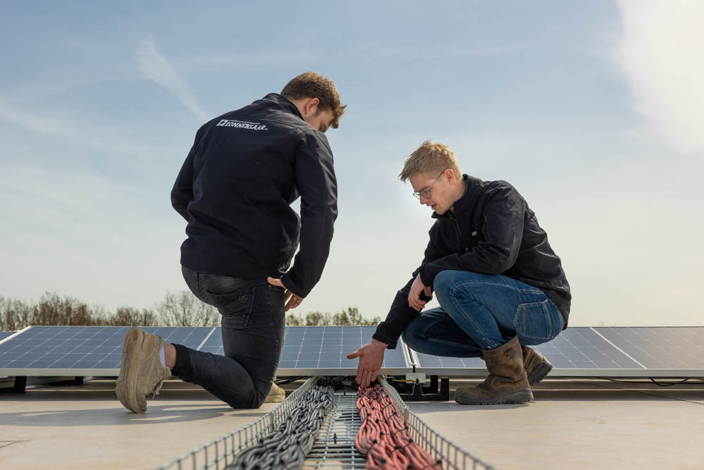 Twee medewerkers van Zonneklaar die bezig zijn met zakelijke zonnepanelen installeren